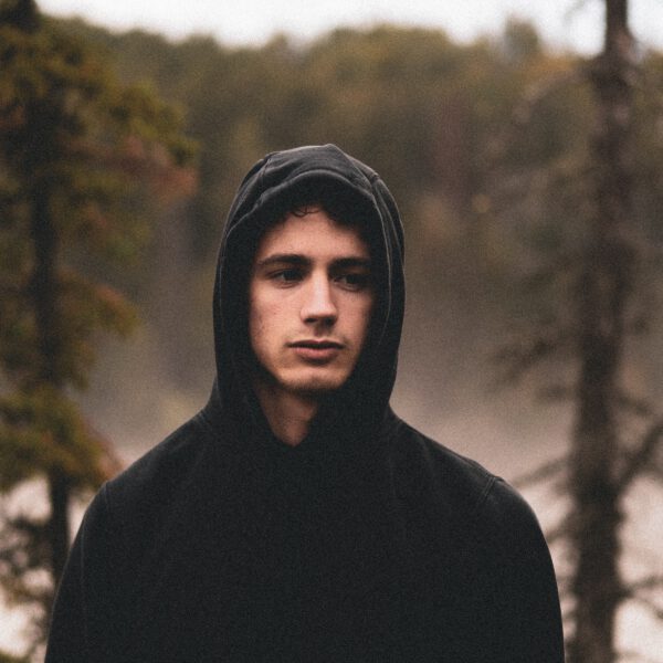 man in front of a forest with a black hoodie (wrldwide)